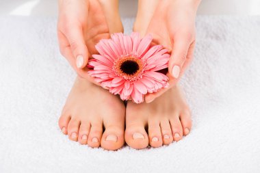 Partial view of barefoot woman standing on towel and holding flower clipart