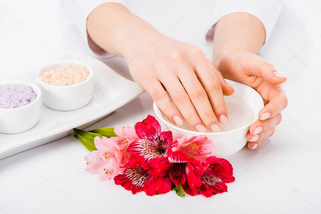 Partial view of woman taking nail bath with flowers