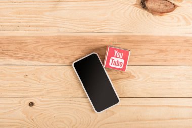 ahşap masa üzerinde youtube simgesi ve smartphone ile boş perde üstten görünüm