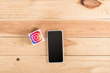 ahşap masa üzerinde instagram simgesinin ve smartphone ile boş perde üstten görünüm