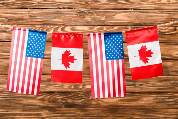 top view of canadian and american flags on wooden background