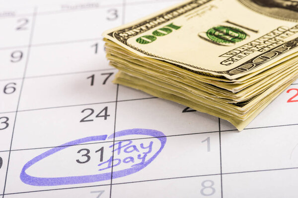 избирательный фокус банкнот в долларах, календарь с маркировкой "31" и "день оплаты"
