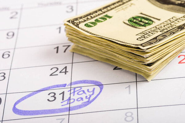 selective focus of dollar banknotes, calendar with marked number 31 and 'pay day' lettering