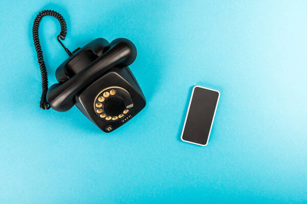 top view of rotary dial telephone and smartphone with copy space isolated on blue