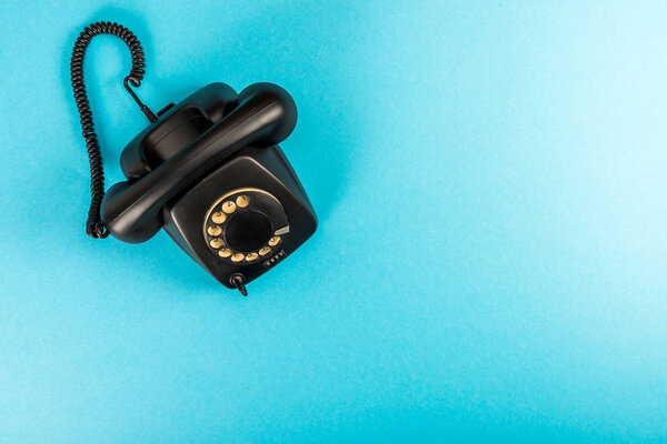 top view of black rotary dial telephone isolated on blue with copy space 