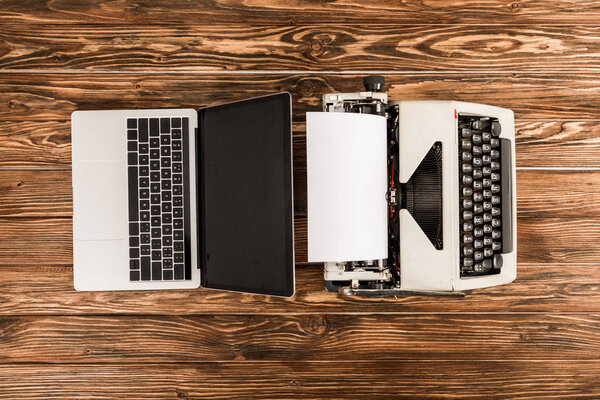 top view of typewriter and laptop on wooden table