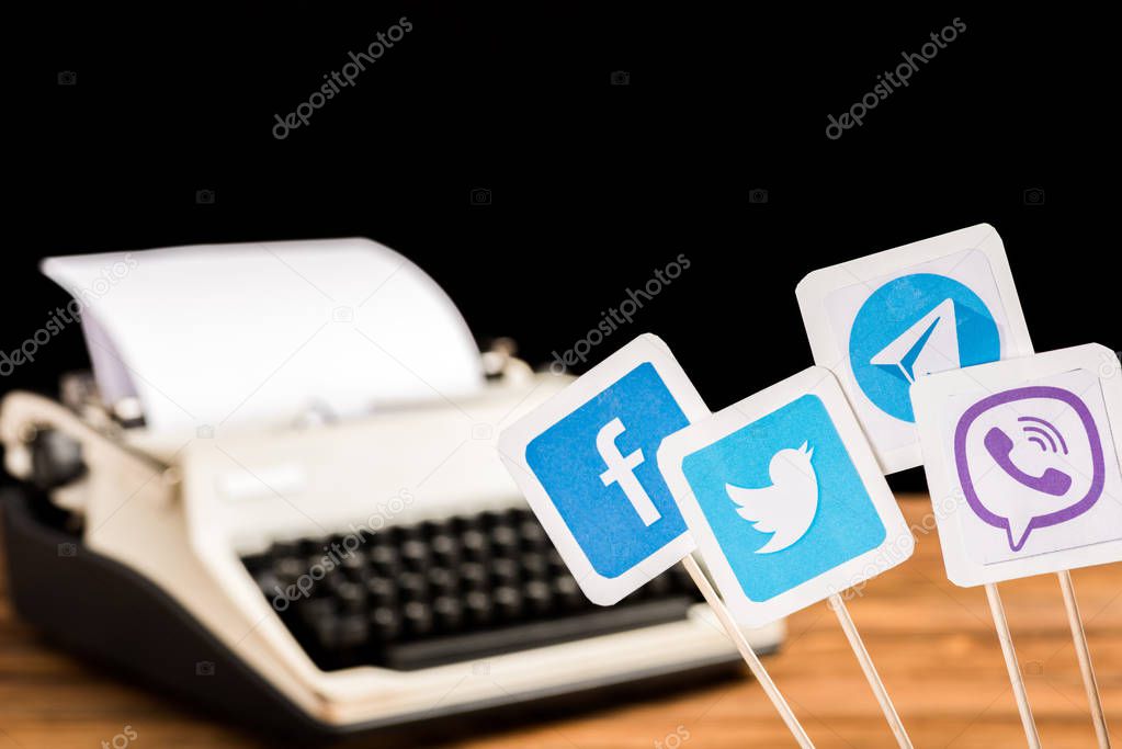 Selective focus of facebook, twitter, viber and telegram icons with typewriter on background