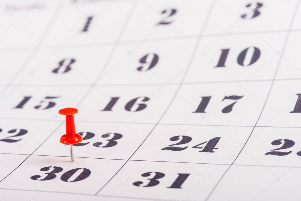 selective focus of red pin on number 30 in calendar