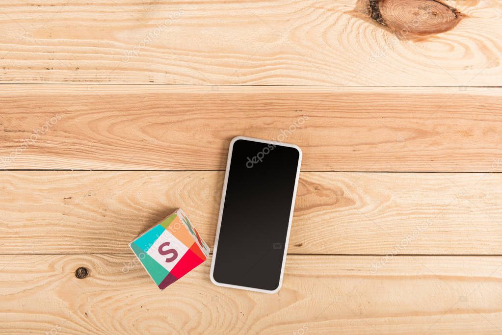 Top view of slack icon and smartphone with blank screen on wooden table