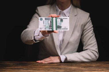 ahşap masada oturan ve üzerinde siyah Rus ruble tutan bir işkadını kırpılmış atış 