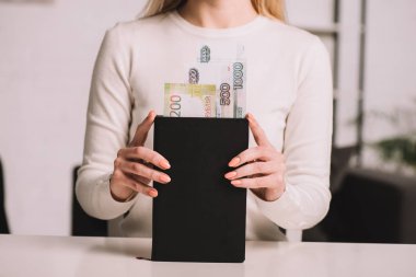 cropped shot of woman holding notebook with russian rubles banknotes clipart