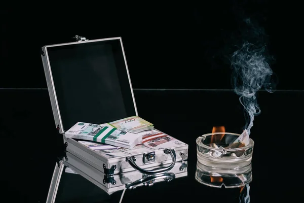 俄罗斯卢布钞票在手提箱保险箱和燃烧的钱在烟灰缸黑色 — 图库照片
