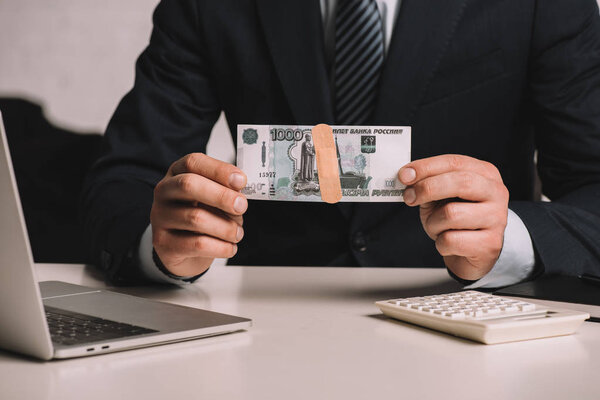 cropped shot of businessman holding russian rubles banknote with medical patch 