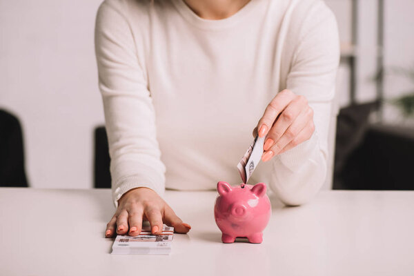 mid section of woman putting russian rubles into piggy bank, savings concept 