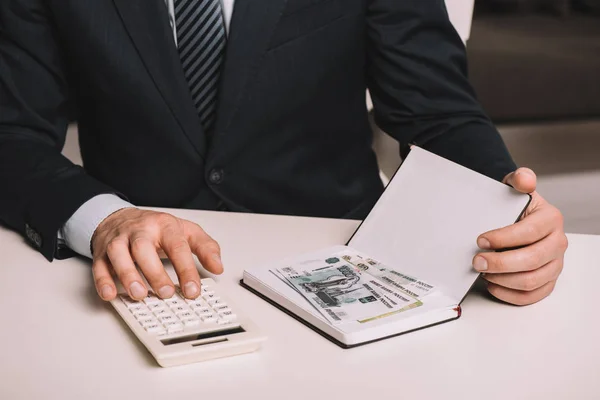 Recortado Tiro Hombre Negocios Utilizando Calculadora Celebración Cuaderno Con Billetes —  Fotos de Stock