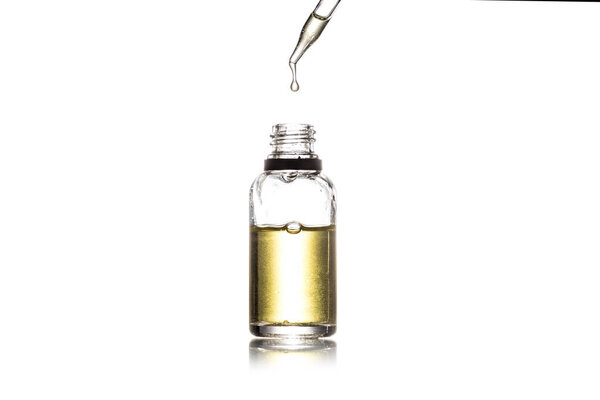 Studio shot of glass bottle with golden liquid and dropper isolated on white