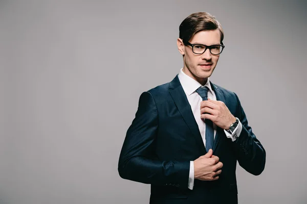 Bonito Homem Terno Tocando Gravata Cinza Fundo — Fotografia de Stock