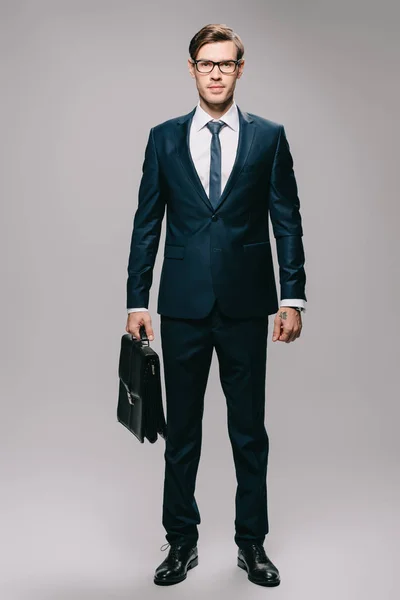 Selbstbewusster Geschäftsmann Anzug Mit Aktentasche Auf Grauem Hintergrund — Stockfoto