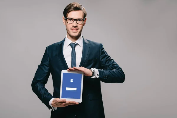 Cheerful Businessman Holding Digital Tablet Facebook App Screen Isolated Grey — Stock Photo, Image