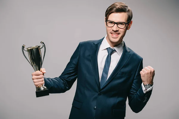 Bonito Empresário Óculos Comemorando Vitória Segurando Troféu Mão Fundo Cinza — Fotografia de Stock