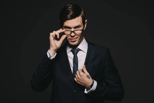 Handsome Businessman Touching Glasses While Standing Suit Isolated Black — Stock Photo, Image