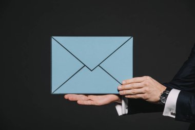 siyah izole mavi bir zarf içerisinde tutan adamın kırpılmış görünümü