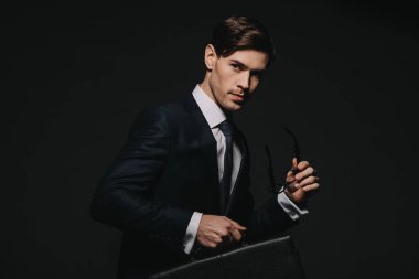 Evrak çantası ve gözlük siyah izole elinde tutan yakışıklı işadamı