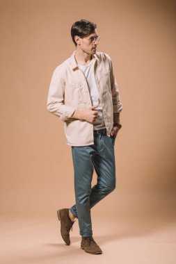 kendine güvenen adam cebinde bej renkli arka plan üzerinde el ile ayakta gözlük