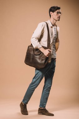 bej renkli arka plan üzerinde çanta ile ayakta bardaklarda ciddi adam 