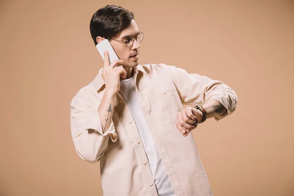 Hombre Guapo Gafas Mirando Reloj Mientras Habla Teléfono Inteligente Aislado —  Fotos de Stock