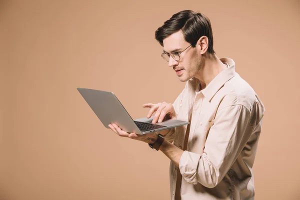Koncentruje Się Człowiek Okularach Pomocą Laptopa Beżowym Tle — Zdjęcie stockowe