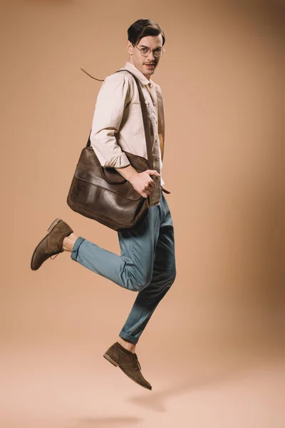 Handsome Man Glasses Jumping Bag Beige Background — Stock Photo, Image