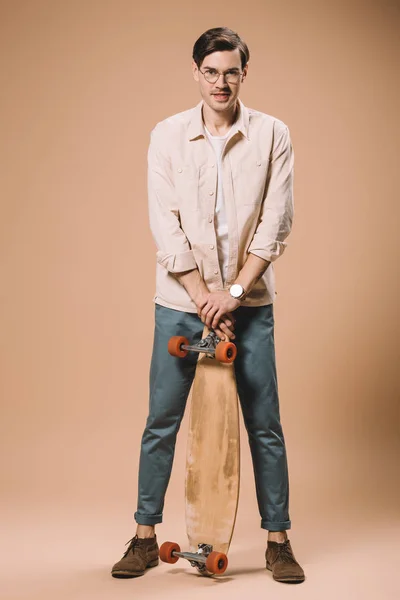 Glücklicher Mann Mit Brille Und Skateboard Auf Beigem Hintergrund — Stockfoto