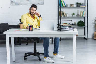 Ofiste çalışan sarı gömlekli sakallı işadamı konsantre
