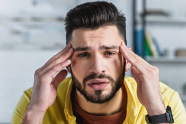 Close up of bearded businessman man touching head at workplace clipart