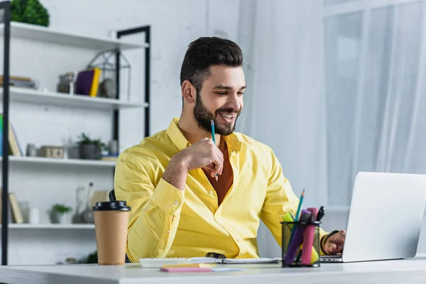 Fröhlicher Geschäftsmann Blickt Auf Laptop Bildschirm Und Hält Bleistift Arbeitsplatz — Stockfoto