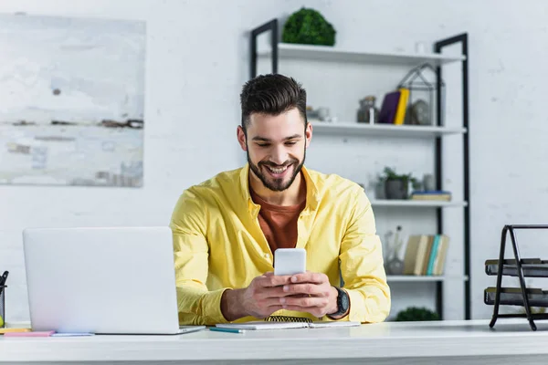 Lächelnder Bärtiger Geschäftsmann Gelben Hemd Blickt Arbeitsplatz Auf Sein Smartphone — Stockfoto