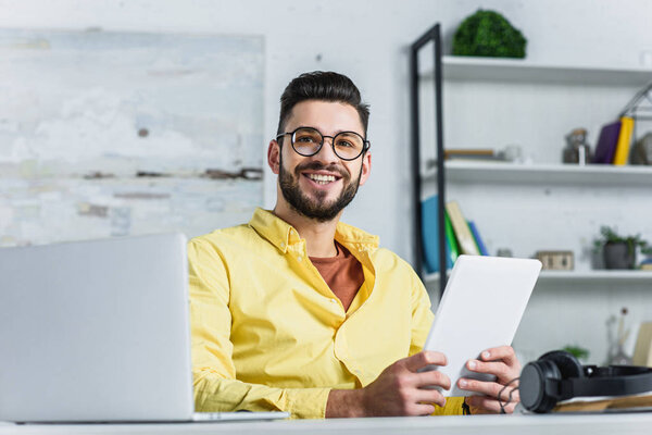 Веселый бизнесмен в очках смотрит в камеру в офисе
