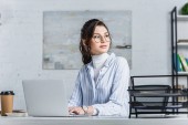 Atraktivní podnikatelka v brýlích pomocí přenosného počítače a hledat dál 