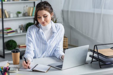 Gülümseyen güzel iş kadını işyerinde not defterinde yazıyor