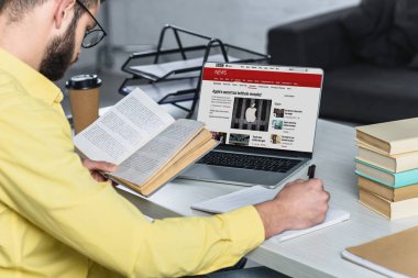 modern ofis ekran laptop bbc Web sitesi ile yakınındaki kitapla okuyan adam sakallı
