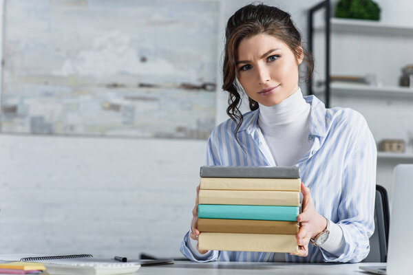 attractive woman holding books in hands in modern office 