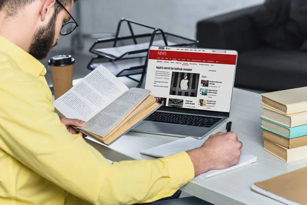 Bearded Man Studying Book Laptop Bbc Website Screen Modern Office — Stock Photo, Image