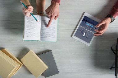 ekranda dijital tablet tumblr app ile yakın kitap parmakla işaret eden adamın üstten görünüm 