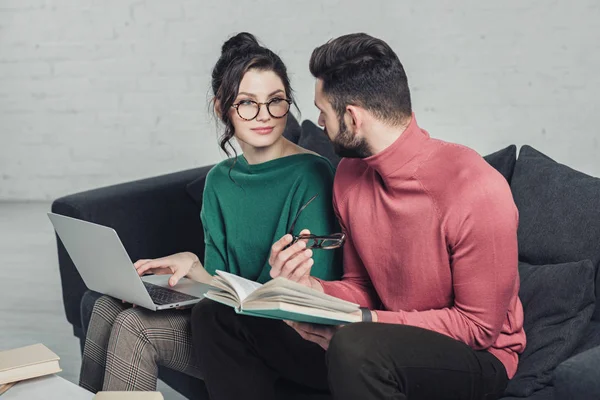 男人看着愉快的女人坐在眼镜与笔记本电脑 — 图库照片