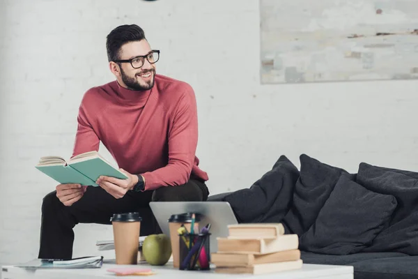 Glad Man Glasögon Sitter Nära Laptop Och Håller Bok — Stockfoto