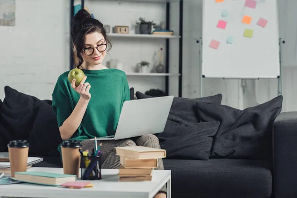 Hermosa Mujer Sosteniendo Manzana Sentado Sofá Con Ordenador Portátil — Foto de Stock