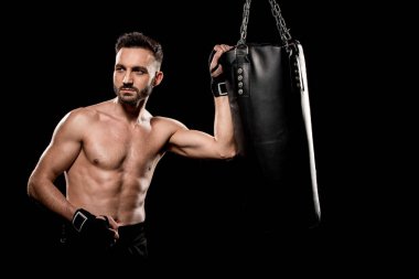 muscular handsome boxer standing near punching bag isolated on black clipart