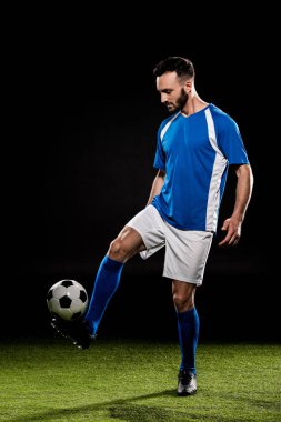 bearded man playing with ball on grass isolated on black clipart