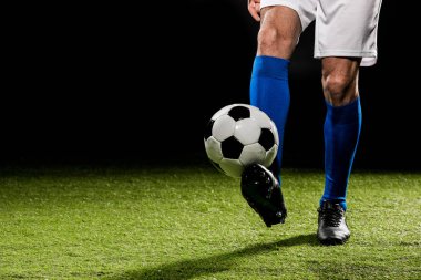 cropped view of man playing with ball on grass isolated on black clipart